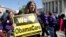 Holding a sign saying "We Love ObamaCare" supporters of health care reform rally in front of the Supreme Court in Washington, Mar. 27, 2012.
