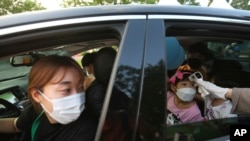 A young girl has her temperature checked as she arrives to watch a drive-in concert at the Gyeongbok Palace parking lot in Seoul, South Korea, July 17, 2020. 