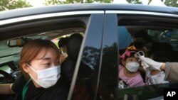 A young girl has her temperature checked as she arrives to watch a drive-in concert at the Gyeongbok Palace parking lot in Seoul, South Korea, July 17, 2020. 