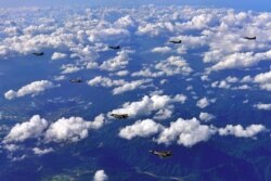 FILE - This handout photo taken on Aug. 31, 2017 and provided by South Korean Defense Ministry in Seoul shows South Korean F-15K fighter jets and U.S. F-35B stealth jet fighters flying over South Korea during a joint military drill.