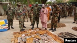 Military officials stand near ammunitions seized from suspected members of Hezbollah after a raid of a building in Kano, Nigeria, May 30, 2013.