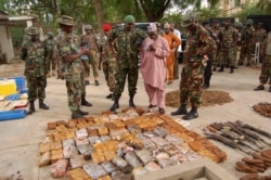FILE - Military officials stand near ammunitions seized from suspected members of Hezbollah after a raid of a building in Kano, Nigeria, May 30, 2013.