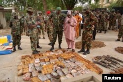 FILE - Military officials stand near ammunitions seized from suspected members of Hezbollah after a raid of a building in Kano, Nigeria, May 30, 2013.
