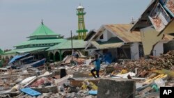 Seorang pria membawa barang-barang yang ditemukannya dari antara puing-puing reruntuhan bangunan di Donggala, Sulawesi Tengah, 2 Oktober 2018. 