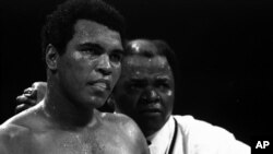 FILE - Muhammad Ali stands with longtime trainer Bundini Brown after Ali became the first man to win the world heavyweight championship three times at the Superdome in New Orleans, September 15, 1978.