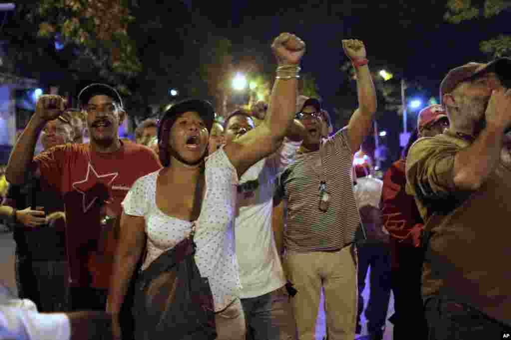 Para pendukung pemerintah Venezuela meneriakkan slogan-slogan yang memuji almarhum Presiden Hugo Chavez, di luar tempat pemungutan suara di Caracas (14/4). (AP/Ariana Cubillos)