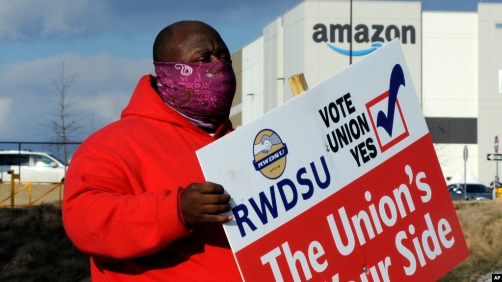 资料照：2月9日在亚马逊贝塞默仓库前，工会成员佛斯特举牌呼吁工人投票同意加入工会 （美联社）(photo:VOA)