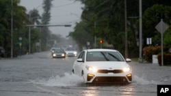 Los automóviles circulan por calles inundadas, el martes 11 de junio de 2024, en Surfside, Florida, EEUU.