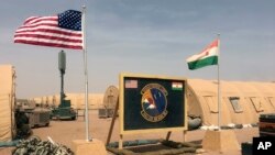 FILE - A U.S. and Niger flag are raised at the base camp for air forces and other personnel supporting the construction of Niger Air Base 201 in Agadez, Niger, April 16, 2018. On the edge of the Sahara Desert, the U.S. is building a base for armed drones.