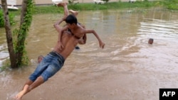 A Cambodian man carries a boy as he leaps into flood waters on the outskirts of Phnom Penh on September 27, 2013.