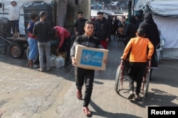 FILE - A Palestinian carries an assistance  container  distributed by the U.N. Relief and Works Agency (UNRWA), amid the Israel-Hamas conflict, successful  Deir al-Balah, cardinal  Gaza Strip, Nov. 4, 2024.