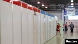 FILE - A woman goes into a cabin at a vaccination center at the Dresden Fair, in Dresden, Germany, July 29, 2021.