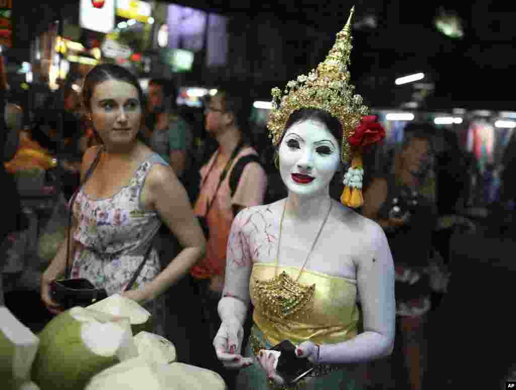 Một phụ nữ Thái Lan hóa trang thành ma nhân dịp Halloween đứng mua dừa ở Bangkok, Thái Lan. 