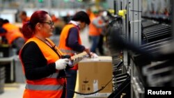 Employees handle packages in the new Amazon logistics center in Dortmund, Germany, Nov. 14, 2017.