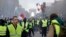 FILE - In this Nov. 24, 2018, file photo, demonstrators, wearing "yellow vests," march on the Champs-Elysees in Paris, France, as they protest the rising of the fuel prices. (AP Photo/Kamil Zihnioglu, File)