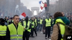 FILE - In this Nov. 24, 2018, file photo, demonstrators, wearing "yellow vests," march on the Champs-Elysees in Paris, France, as they protest the rising of the fuel prices. (AP Photo/Kamil Zihnioglu, File)