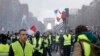 FILE - In this Nov. 24, 2018 photo, demonstrators, wearing 'yellow vests,' march on the Champs-Elysees in Paris, France, as they protest the rising of the fuel prices. 