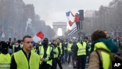 FILE - In this Nov. 24, 2018 photo, demonstrators, wearing 'yellow vests,' march on the Champs-Elysees in Paris, France, as they protest the rising of the fuel prices. 