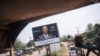 FILE - A convoy of the U.N. Multidimensional Integrated Stabilization Mission in the Central African Republic passes by an election poster of opposition candidate Anicet Georges Dologuélé, in Bangui, Dec. 25, 2020. 