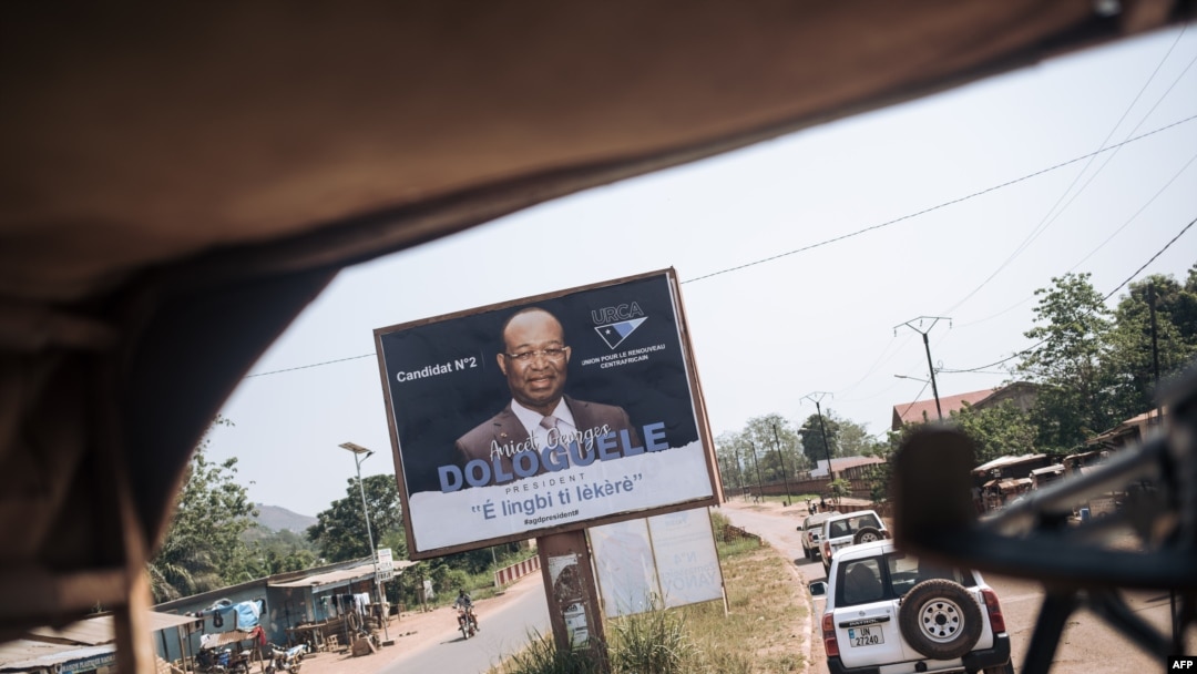 FILE - A convoy of the U.N. Multidimensional Integrated Stabilization Mission in the Central African Republic passes by an election poster of opposition candidate Anicet Georges Dologuélé, in Bangui, Dec. 25, 2020. 
