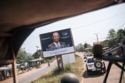 A convoy of the U.N. Multidimensional Integrated Stabilization Mission in the Central African Republic passes by an election poster of opposition candidate Anicet Georges Dologuélé, in Bangui, Dec. 25, 2020.