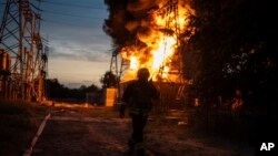 (FILE) A Ukrainian firefighter talks on the radio while he works to extinguish the fire on the site of an electrical substation that was hit by Russian strike in Dnipropetrovsk region, Ukraine, Monday, Sept. 2, 2024.