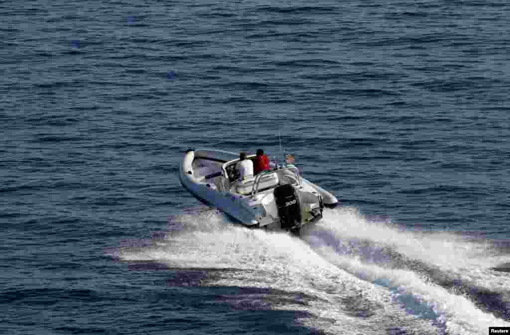 Suspected migrant and refugee smugglers power their speed boat back towards Turkey after dropping off a load of Syrian refugees at a remote beach on the Greek island of Lesbos.