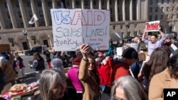 FILE - Barbara Singer of Bethesda, Md., who says she was let go from her USAID job in early February, shows her support of USAID, Feb. 28, 2025, in Washington. "It's a great agency that benefits all of us," she said, "Americans and people worldwide."