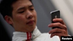 A man looks at the screen of his iPhone as he walks on a busy street in downtown Shanghai, March 13, 2013. 