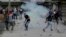Kashmiri protesters shout slogans as a tear gas shell explodes near them in Srinagar, Indian-controlled Kashmir, May 12, 2017. Government forces used tear gas smoke and rubber bullets to disperse dozens of rock-throwing protesters demonstrating against Indian rule in Kashmir Friday.