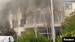 Smoke rises from a building as people gather during a protest, in Sweida, Syria, Dec. 4, 2022, in this screen grab obtained from a social media video. (Suwayda 24/via REUTERS) 