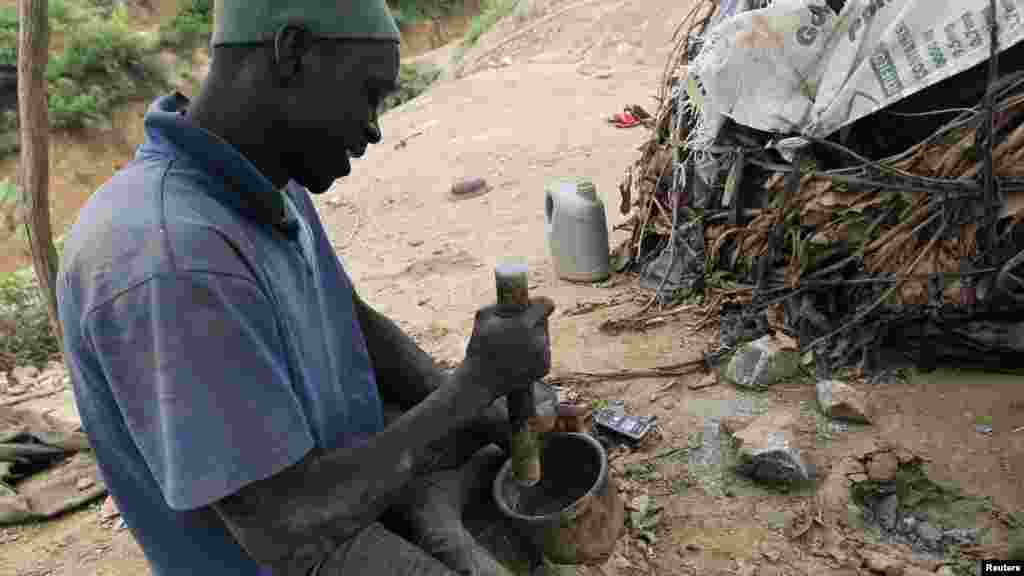 A man crushes rock samples in a bowl before testing them for gold at a mine in Minna, Niger State.