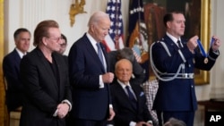 O Presidente Joe Biden, ao centro, prepara-se para entregar a Medalha Presidencial da Liberdade, a mais alta condecoração civil da Nação, a Bono, à esquerda, na Sala Leste da Casa Branca, no sábado, 4 de janeiro de 2025, em Washington.