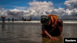 Seorang pengungsi Rohingya menyentuh pasir di pantai Bengal, Shah Porir Dwip, Bangladesh, 11 September 2017, setibanya di kawasan itu. (Foto: dok). Militer Malaysia mengukuhkan pihaknya menghalau sedikitnya satu perahu mencurigakan yang penuh berisi orang Rohingya, Jumat (17/4).