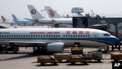 Airport worker unloads passenger luggage into a Shenzhen Airliner parked at the Beijing International Aiport in Beijing, China, Aug. 15, 2007.