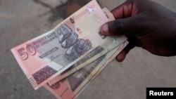 FILE - A man shows off Zimbabwean currency notes outside a grocery store in Harare, Zimbabwe, March 17, 2022. Picture taken March 17, 2022. 