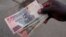 FILE - A man shows off Zimbabwean currency notes outside a grocery store in Harare, Zimbabwe, March 17, 2022. Picture taken March 17, 2022. 