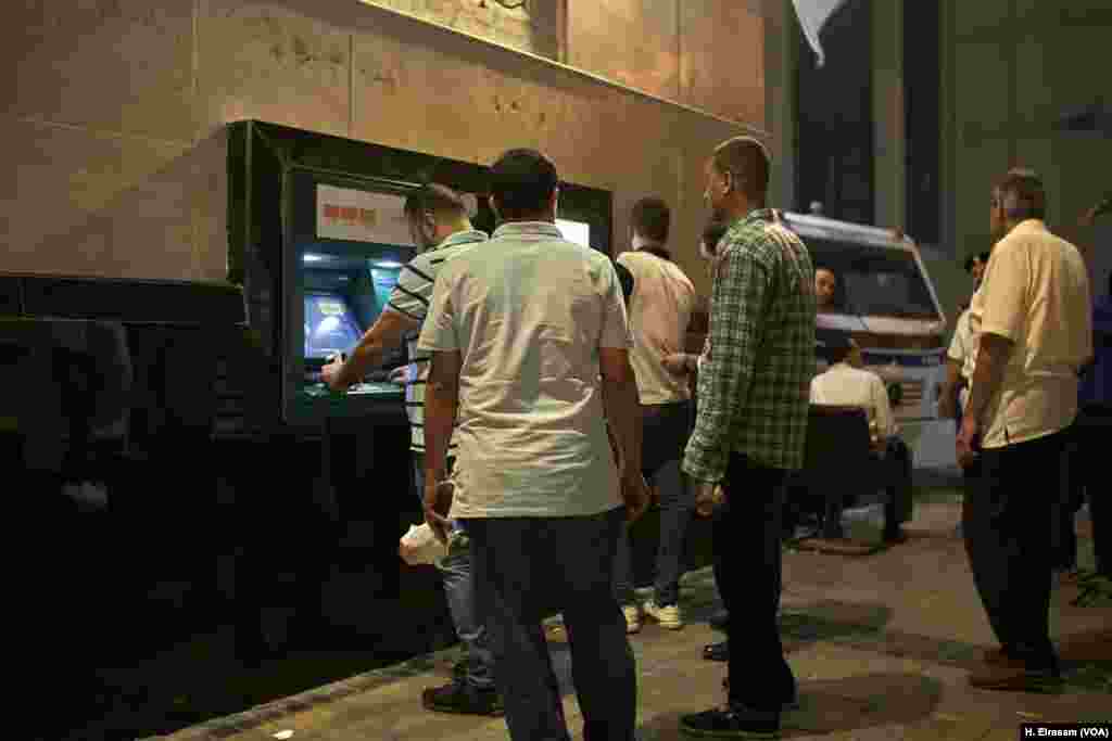 Bank customers line up for cash at an ATM in central Cairo. Welcoming Eid means spending money on feasts, clothes, and gifts – usually cookies – for friends and family. 