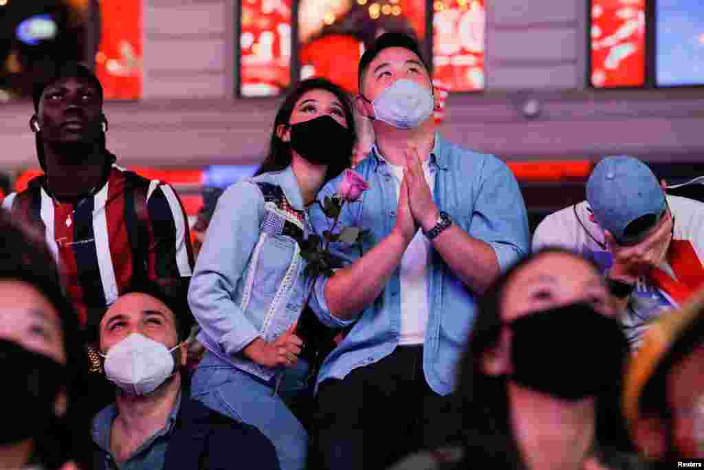 People react as they watch a speech by Democratic 2020 U.S. presidential nominee Joe Biden after news media announced that he has won the 2020 U.S. presidential election, on Times Square in New York.