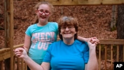 Maggie Hill, 67, poses for a portrait with a 10-year-old Charity in Madison, W.Va., on Thursday, Nov. 29, 2018. The grandmother is raising Charity, the daughter of Maggie's son, as her own child. (AP Photo/Tyler Evert)