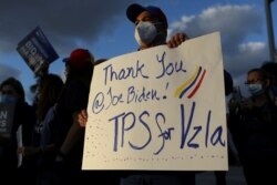 FILE - A man holds a sign as members of the Venezuelan community react after the Biden administration said it would grant temporary protected status to Venezuelan migrants living in the United States, in Doral, Florida, March 9, 2021.