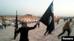 An armed fighter of the Islamic State of Iraq and the Levant waves an ISIL flag in the city of Mosul, Iraq, June 23, 2014.