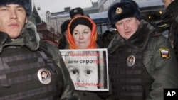Police officers detain a protester near the State Duma, in Moscow, Russia, Wednesday, Dec. 19, 2012. The poster reads: Are orphans guilty of Magnitsky's death? Stop putting shame on yourselves! 