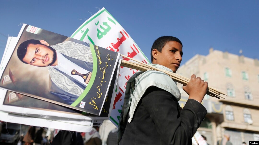 FILE - A supporter carries posters depicting Houthi leader Abdel-Malek al-Houthi during a rally in Sana'a, Yemen, March 6, 2015.
