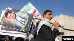 FILE - A supporter carries posters depicting Houthi leader Abdel-Malek al-Houthi during a rally in Sana'a, Yemen, March 6, 2015.