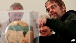 FILE - Brother Guy Consolmagno, a Jesuit astronomer, right, shows visitors a globe of the planet Mars, at the Vatican Observatory outside Rome, April 15, 2011.