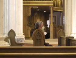 A congregant wears a face mask before mass at the Cathedral of St. Helena in Helena, Mont., April 26, 2020. Church services resumed in Montana as the state began to ease restrictions meant to stop the spread of the coronavirus.