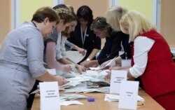 FILE - Members of a local election commission sort ballots before starting to count votes after the parliamentary election in Minsk, Belarus, Nov. 17, 2019.