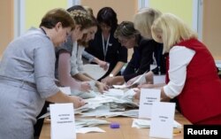 FILE - Members of a local election commission sort ballots before starting to count votes after the parliamentary election in Minsk, Belarus, Nov. 17, 2019.
