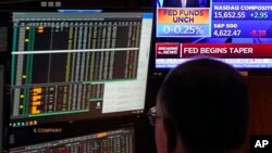 A television screen on the floor of the New York Stock Exchange shows a rate decision of the Federal Reserve, in New York City, Nov. 3, 2021. The Federal Reserve will begin dialing back the economic aid it's provided in response to the COVID-19 pandemic.